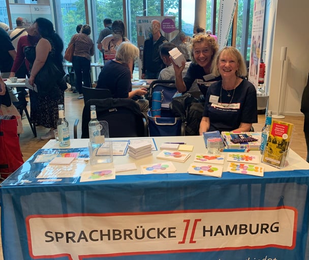 Sprachbrücke-Hamburg e.V. war mit einem Stand auf der „Integrationsmesse Bergedorf“ vertreten. Auf dem Bild sind zwei gut gestimmte Mitarbeiterinnen zu sehen.